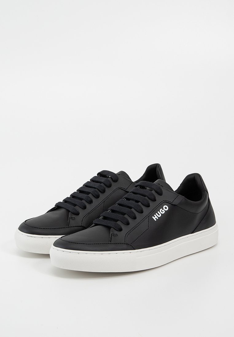Schwarze Ledersneaker mit weißer Gummisohle. Merkmale sind runde Schnürsenkel, ein Logo an der Seite und eine glatte Oberfläche.