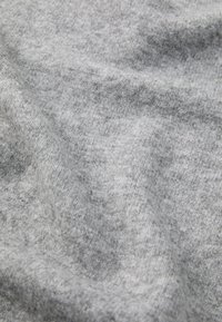 Grått stickat tyg med en mjuk textur och subtil melering, med en något ojämn yta som ger djup och dimension.