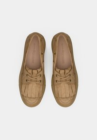 Καφέ αναπαυτικά παπούτσια από καστόρι με στρογγυλεμένη μύτη, κλείσιμο με κορδόνια και διακοσμητικό κρόσσι στο άνω μέρος. Υφή σόλας με ορατή ραφή.
