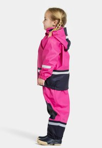 Ljusrosa vattentät regnjacka med huva, i kombination med matchande rosa och marinblå byxor. Har elastiska ärmslut och reflexer.