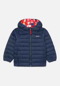 Marineblaue Pufferjacke mit rotem Innenfutter, das mit einem bunten geometrischen Muster versehen ist, einem Reißverschluss auf der Vorderseite und elastischen Bündchen.