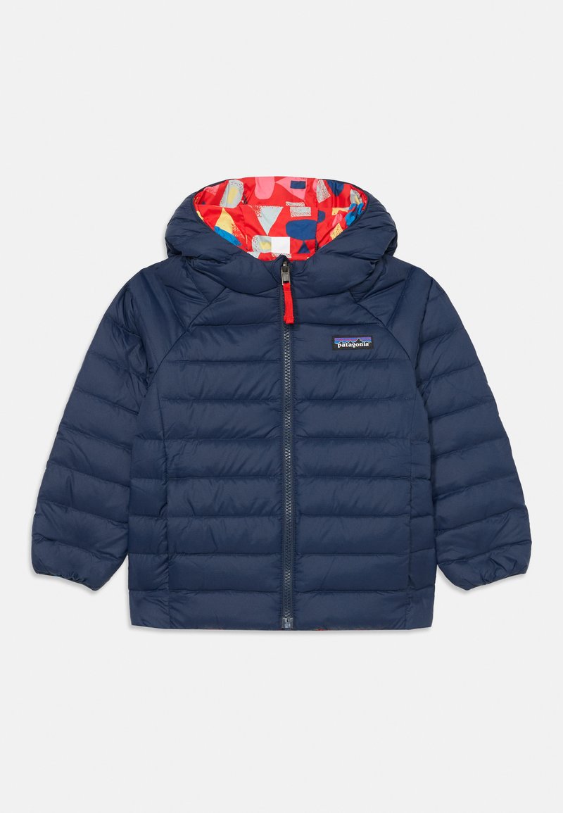 Marineblaue Pufferjacke mit rotem Innenfutter, das mit einem bunten geometrischen Muster versehen ist, einem Reißverschluss auf der Vorderseite und elastischen Bündchen.