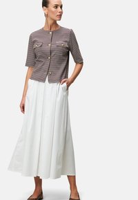 Gestreepte korte mouwen cardigan met gouden knopen en twee borstzakken, gecombineerd met een vloeiende witte maxi rok met zijzakken.