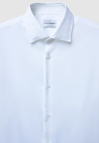 Camicia bianca slim fit con colletto a punta e tre bottoni frontali visibili, etichettata Calliope, taglia grande, in tessuto facile da stirare.