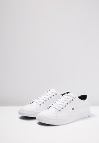 Białe skórzane sneakersy z okrągłym noskiem i płaską gumową podeszwą, wyposażone w zapięcie na sznurowadła oraz mały detal z logo po boku.