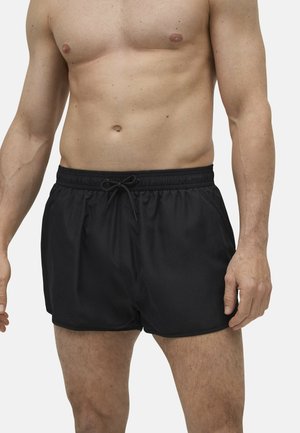 Shorts de baño negros hechos de un tejido ligero con cinturilla elástica, detalle de cordón y bolsillos laterales. Diseño sencillo y minimalista.