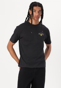 Zwarte katoenen t-shirt met korte mouwen, voorzien van een kleurrijk Billabong-logo op de bovenste linker borstpartij. Eenvoudig ronde hals ontwerp.