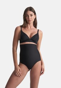 Set bikini nero con reggiseno senza fili e design incrociato, pantaloni a vita alta. Tessuto liscio e elasticizzato con finitura opaca.