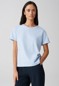 Lichtblauw katoenen t-shirt met een ronde halslijn, opgerolde korte mouwen en een klein geborduurd logo op de borst. Casual pasvorm, zachte textuur.