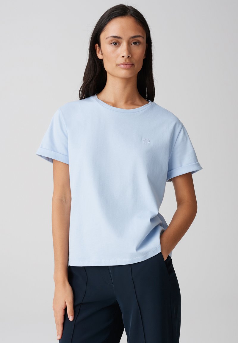 Lichtblauw katoenen t-shirt met een ronde halslijn, opgerolde korte mouwen en een klein geborduurd logo op de borst. Casual pasvorm, zachte textuur.