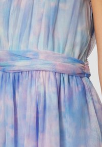 Ein ärmelloses Kleid aus durchsichtigem, leichtem Stoff in sanften Pastellfarben, mit einer gerafften Taille und einer hellblauen Schleife.