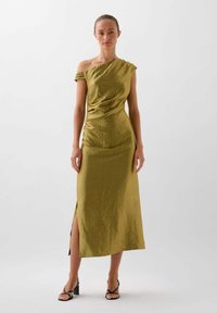 Asymmetriska olivgröna klänningen med en texturerad yta, knä-hög slits på sidan och korta, rullade ärmar.