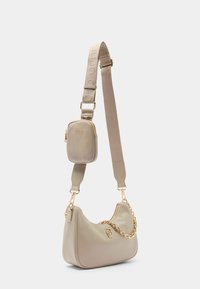 Borsa a tracolla in pelle beige con dettaglio in catena dorata, tracolla regolabile e piccola pochette con zip. Texture liscia e forma curva.