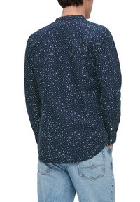 Marineblauwe longsleeve shirt met een verspreid wit patroon, knoopmanchetten en een ronde zoom. Draag het met lichtblauwe denim jeans.