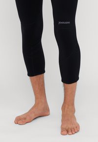 Juodos, priglundančios sportinės legging kelnių iki kelių su tekstūruotu paviršiumi, sustiprintomis siūlėmis ir subtiliu logotipu šalia kelio.