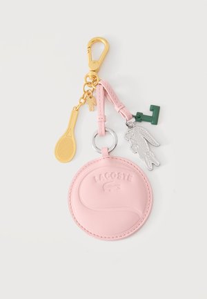 Goldener Schlüsselanhänger mit pinkfarbenem Tennisballtäschchen, silbernem Lacoste-Krokodil-Anhänger, grünem Buchstaben F und goldenem Tennisschläger-Anhänger.