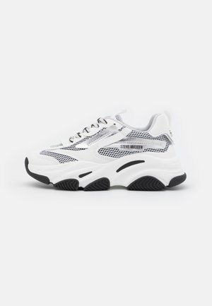 Biało-szary masywny sneaker z czarnymi akcentami, siateczkowymi detalami, sznurowaniem z przodu i logo Steve Madden po boku.