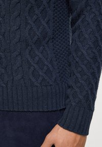 Granatowy sweter z splotem, wykonany z wełny, z wzorami warkoczowymi i teksturowymi. Ribbowane mankiety i dół. Wykonany z grubej przędzy dla ciepła i komfortu.