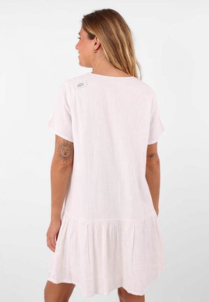 Robe blanche à manches courtes avec un design fluide, présentant un ourlet froncé. Fabriquée en tissu léger, comprend une étiquette près de l'encolure.