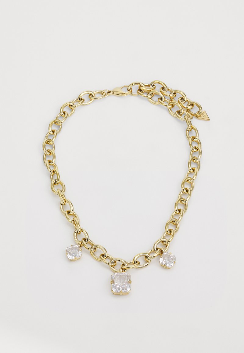 Gouden ketting met drie heldere vierkante stenen, twee kleinere en een grotere, gezet in metalen sluitingen. Textuur in de schakels creëert diepte.