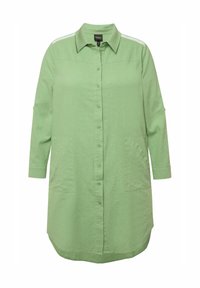 Camicia verde con bottoni, colletto, maniche a trequarti, tasche frontali e strisce laterali. Realizzata in un tessuto leggero e testurizzato.