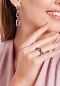 Zilveren kettingoorringen en een bijpassende ring. De oorringen hebben langgerekte schakels; de ring heeft een bicolor ontwerp met gepolijste accenten.