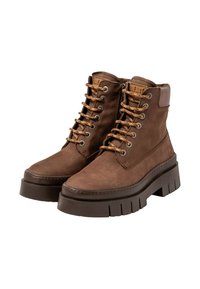 Botas de cuero marrón hasta el tobillo con una suela gruesa y texturizada, diseño de cordones y lazadas en tono marrón claro. Cuentan con un cuello acolchado y el logotipo de la marca en la lengüeta.