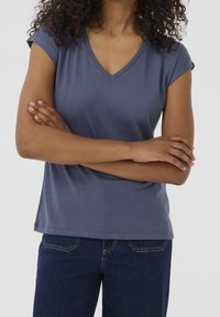 Mörkblå T-shirt med V-ringning och korta ärmar. Mjuk textur, avslappnad passform och enkel fåll. Bärs med mörkblå jeans.