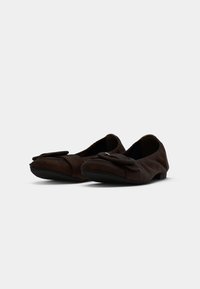 Ballerines en daim marron avec un bout arrondi et un grand nœud à l'avant, dotées d'une semelle en caoutchouc basse pour le confort et la flexibilité.