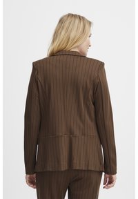 Brunrandig kavaj med strukturerade axlar, skräddarsydd passform, långa ärmar och ryggspringa. Tillverkad av elastisk, texturerad tyg.