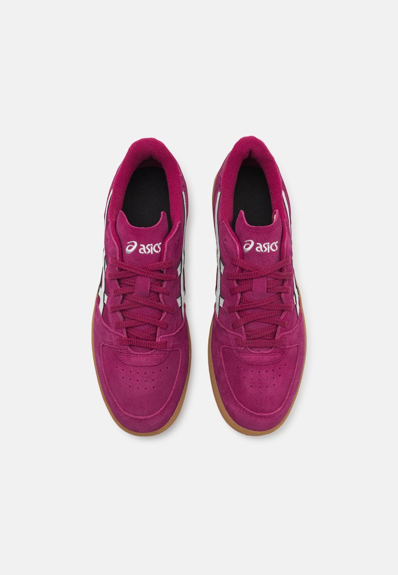Baskets de sport en suède magenta avec doublure en maille noire, logo blanc, et semelle en caoutchouc naturel, présentant des détails perforés et un système de laçage.