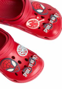 Red plastic clogs featuring Spider-Man character graphics and text. Ventilation holes on the sides, textured footbed for grip.