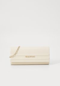 Kremowa torebka kopertowa o teksturowanej powierzchni, z złotymi elementami i łańcuszkowym paskiem. Wytłoczone logo widoczne z przodu.