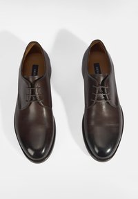 Chaussures habillées en cuir marron avec une finition lisse, un bout rond et des détails de lacets. Présentent une texture subtile et des coutures contrastées.