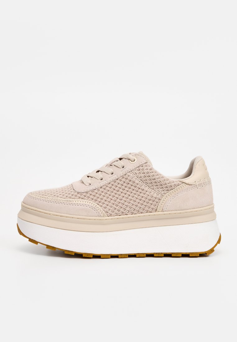 Beige Schnürschuh aus strukturiertem Mesh-Obermaterial mit glatten Wildleder-Details, ausgestattet mit einer klobigen weißen Gummisohle für zusätzlichen Schwung.