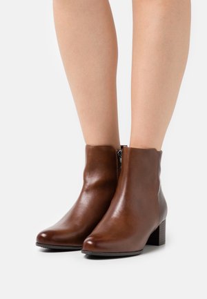 Brown leather ankle boots with a sleek design, rounded toe, and a stacked heel. Features a side zipper for easy wear.