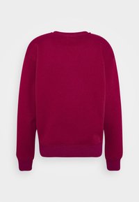 Fleece-tröja i djup magenta, med rund halsringning, ribbade ärmslut och rak fåll. Slät textur med en enkel design.