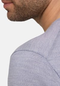 Tessuto di maglia blu chiaro e morbido di una t-shirt, con colletto rotondo e cuciture dettagliate sulle spalle e sul collo per una maggiore struttura.