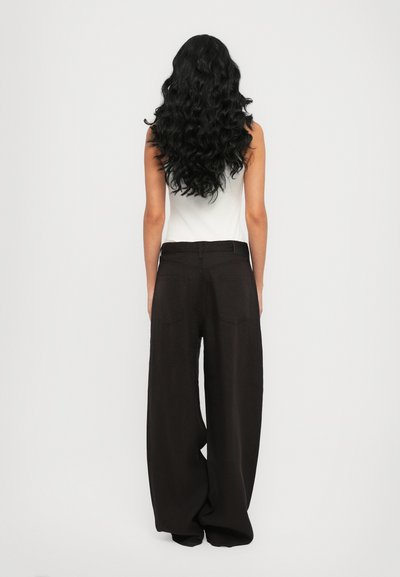 Pantalones negros de pierna ancha, hechos de tela ligera, con una cintura alta, presillas para cinturón y dos bolsillos traseros, mostrados por la parte de atrás.