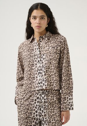 Chemise à manches longues en imprimé léopard, en tissu doux, avec un devant boutonné, deux poches poitrine et un design cropped.