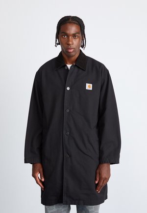 Black coat with a corduroy collar, front snap buttons, two side pockets, and a small logo patch on the left chest. Durable fabric texture.