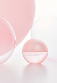 Contenant sphérique rose étiqueté « Abib PDRN collagen lip mask glazed jelly », entouré d'orbes translucides roses et blanches sur un fond clair.