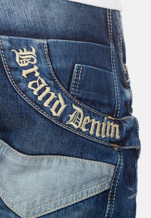 Denim jeans featuring dark blue fabric, contrasting light blue accents, and embroidered "Grand Denim" text on the back pocket.