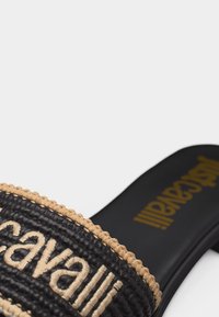 Μαύρο σανδάλι slide με υφαντή μπεζ διακόσμηση και την κεντητή λέξη «Maravalli» στη μπεζ κορδέλα.