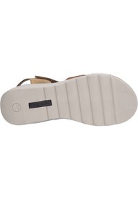 Light brown leather sandal with adjustable straps, featuring a textured white rubber sole and prominent brand logo on the side.