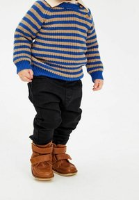 Suéter de rayas en azul y marr�ón claro, con cuello redondo, pantalones negros y botas de tiras marrones, destacando la textura y la forma.