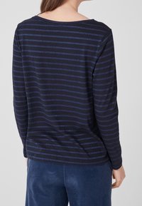 Mörkblå långärmad skjorta med horisontella blå ränder, med rund hals och avslappnad passform. Mjuk tyg med lätt glans.