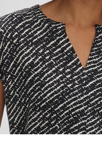 Black and white patterned top with a V-neck design, short sleeves, and a textured fabric featuring irregular horizontal stripes.