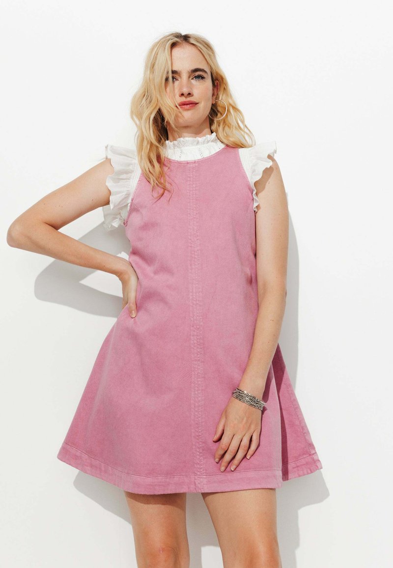 Robe en denim rose avec une forme évasée en A, dotée de manches blanches à volants et d'une couture centrale sur le devant. Tissu lisse et texturé.