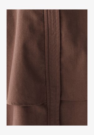 Brūns audums ar gludu tekstūru, ar slāņu dizainu un tīrām šuvēm gar malām un šuvēm. Nav redzamu rakstu vai akcentu.